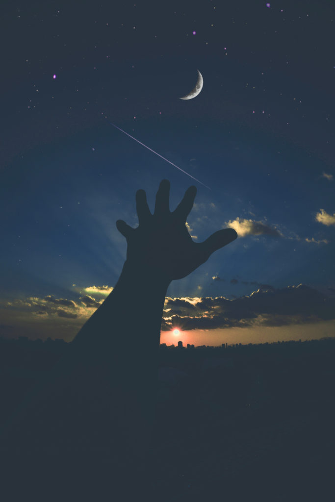 Human hand connecting to sky, stars, crescent moon and sun above Earth's horizon